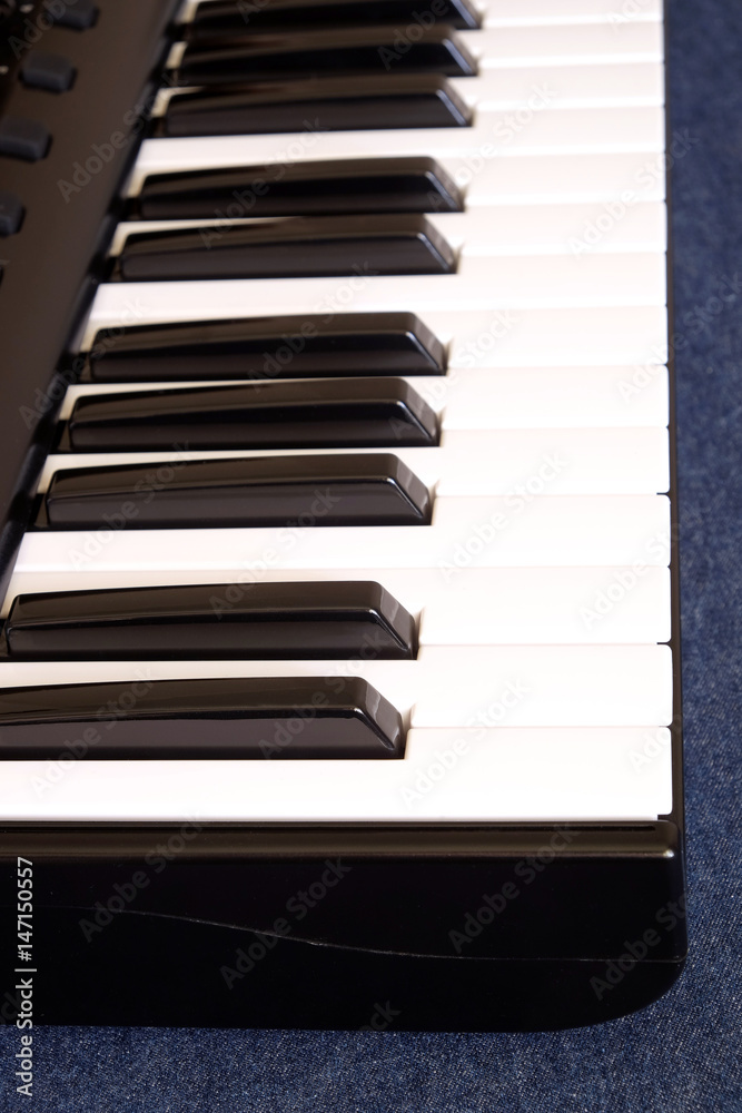 Piano keyboard with black and white keys on blue jeans background side view vertical photo close up Piano keyboard with black and white keys on blue jeans background side view vertical photo close up