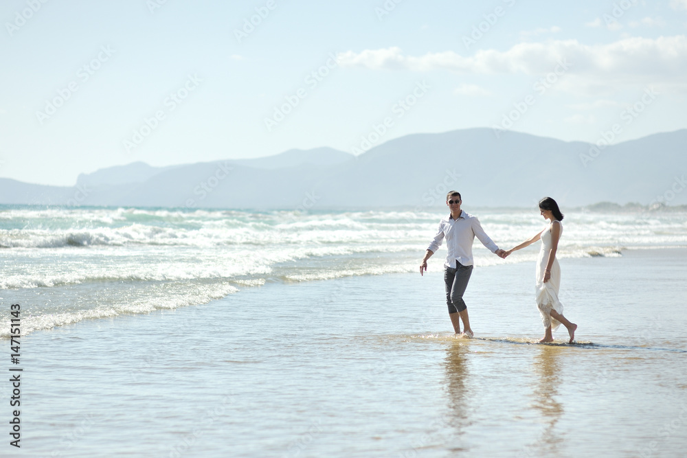 Couple walking holding hands on the beach of Sperlonga, Italy
