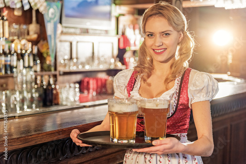 Cheerful woman holding tray with beer glasses