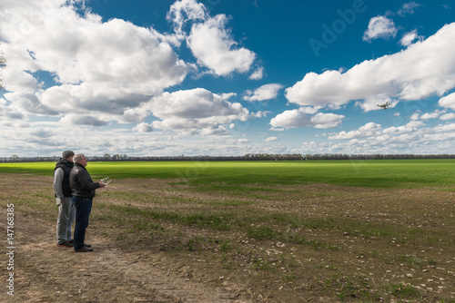 father and son operating of flying drone quadrocopter at the green field