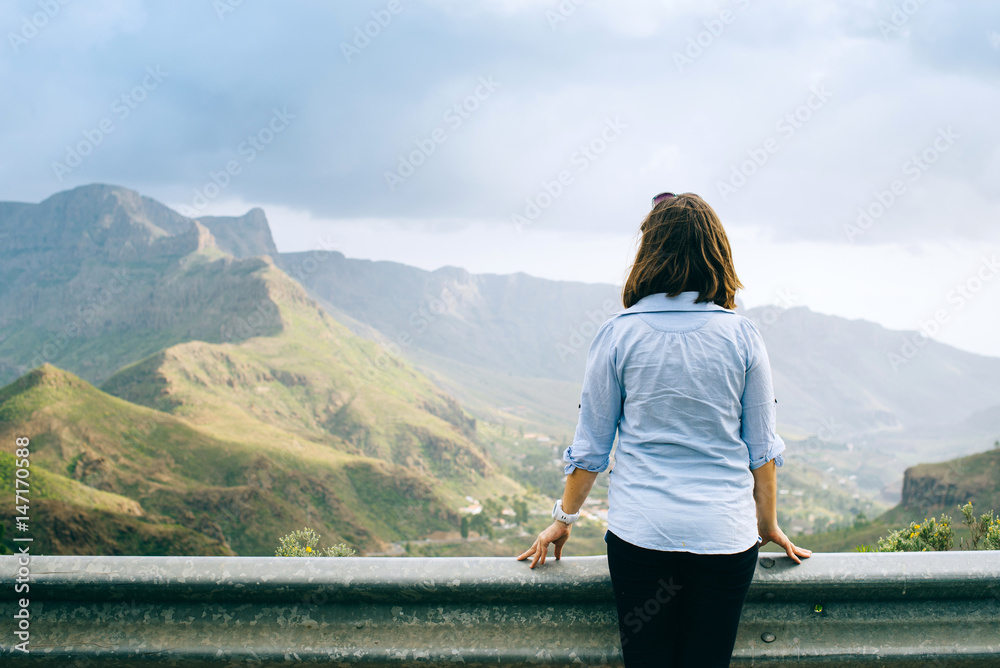 Girl in casual clothes admires views of the mountains in the Canary Islands, Spain