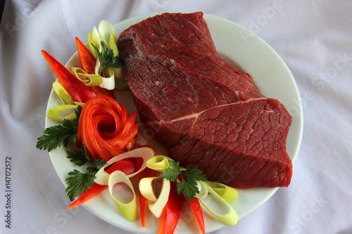 Fresh raw beef on the plate with vegetables