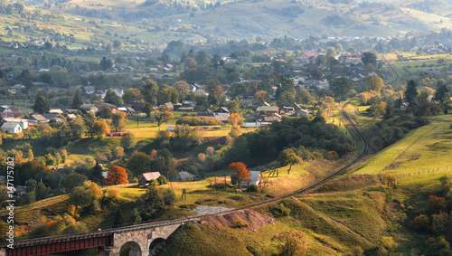 Autumn landscape with a railway, mountains and a village located on the slopes of the mountains.Transcarpathia, the border of Western Ukraine and Romania. Autumn pastoral.