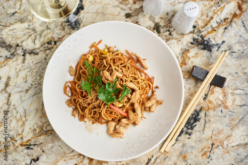 Photography Thin egg noodles with chicken slices served on white plate with white garlic and