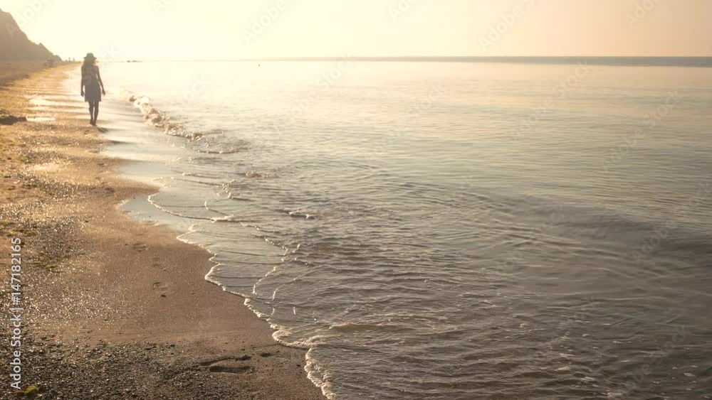 Woman on sunny seashore. Lady walking near water. Woman on sunny seashore. Lady walking near water.