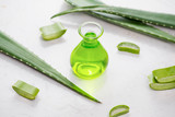 Aloe vera essential oil and aloe leaves on a white background.