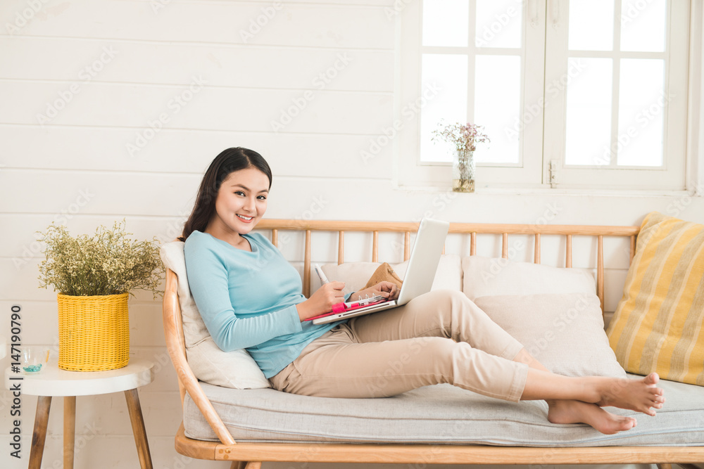 Happy young asian entrepreneur working with a laptop at home.
