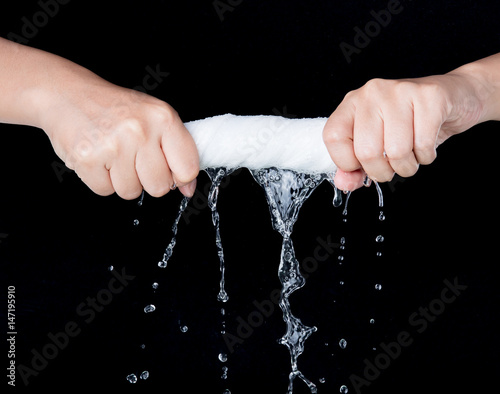 Hand squeeze wet fabric over dark background