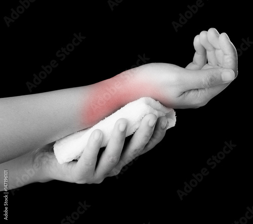 Woman applying cold fabric on arm after accident over dark background,Medical concept photo