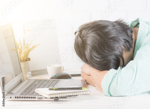 Tired businesswoman sleeping on the desk in front of laptop
