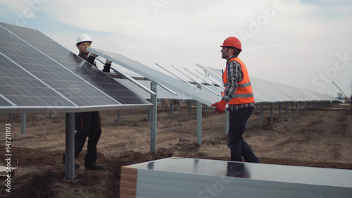 Two builders workers mounting the panels for the solar energy using. photo