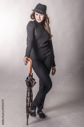 Beautiful young girl in a black hat and with an umbrella

