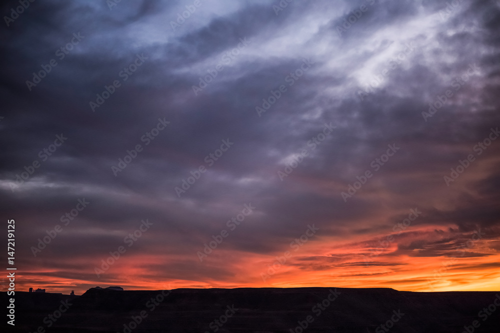 Dramatic colorful red purple and stormy sunset in goosenecks park in Utah with canyons