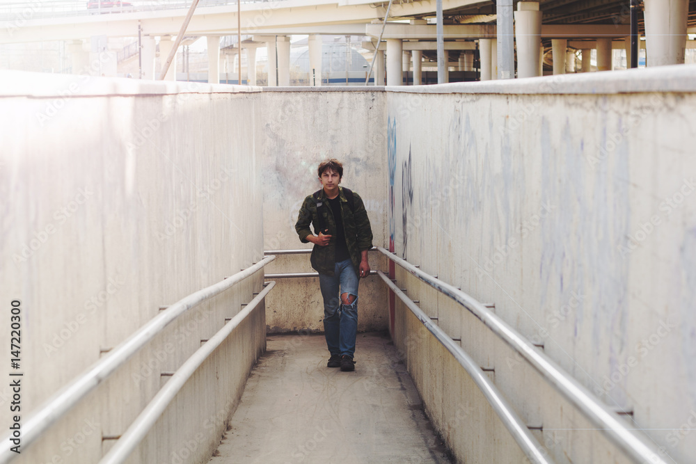 young man with a backpack coming out of the underpass