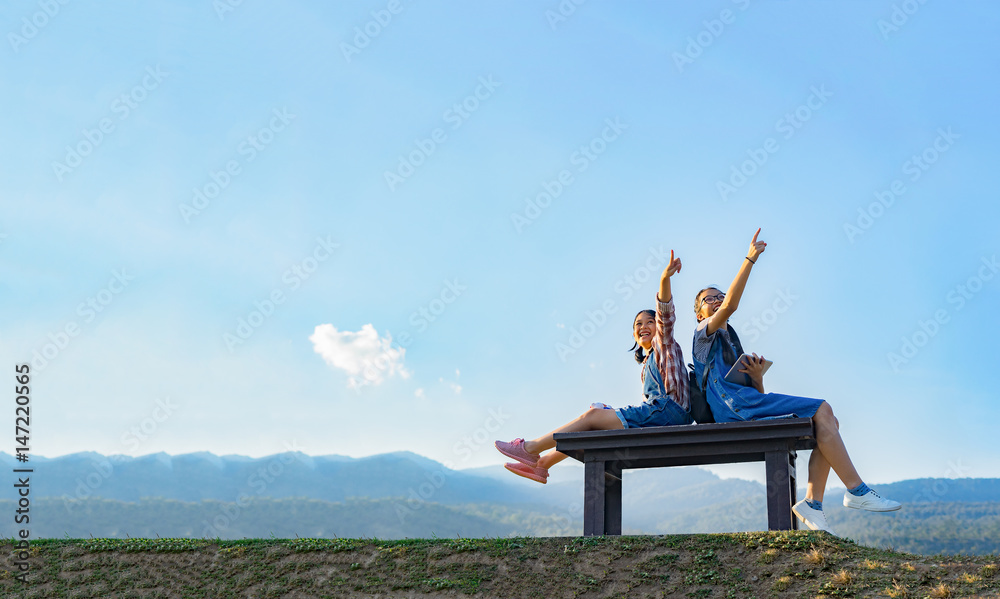two young girlfriends in jeans wear outdoors sitting laughing having good time,hands pointing something,selective focus,communication and friendship ,education concept,copy space for display product