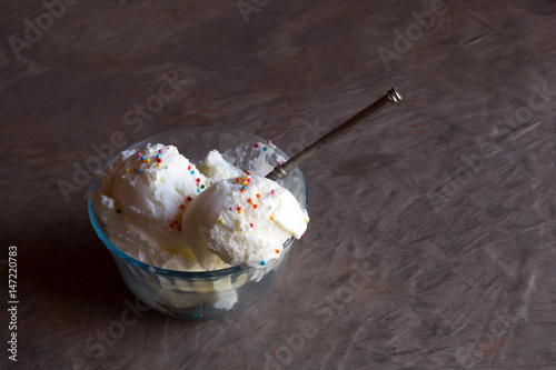 ice cream with candy sprinkles in a vintage saucer and a silver spoon close up