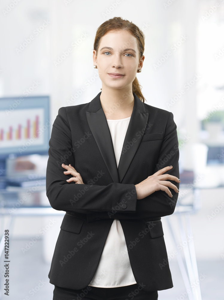Confident professional woman. Shot of a smiling young businesswoman standing in the office with arms crossed. Confident professional woman. Shot of a smiling young businesswoman standing in the office with arms crossed.