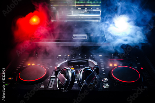 Fotografie DJ Spinning, Mixing, and Scratching in a Night Club, Hands of dj tweak various track controls on dj's deck, strobe lights and fog, selective focus, close up