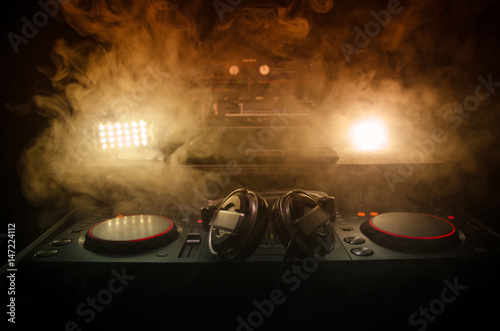 Obraz na plátně DJ Spinning, Mixing, and Scratching in a Night Club, Hands of dj tweak various track controls on dj's deck, strobe lights and fog, selective focus, close up