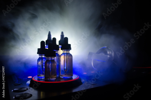 Vape and DJ Club concept. Smoke clouds and vape liquid bottles on Dj mixer close up. Light effects. Useful as background or vape or club advertisement or vape background.