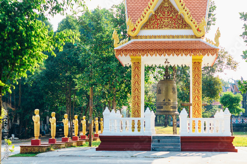 The details of colorful Chotaknhean Pagoda (Temple / Wat ) complex in Krong Khemara Phoumin - Bonsho (Buddhist bell) and golden figures of monks,  Koh Kong Province, Cambodia photo