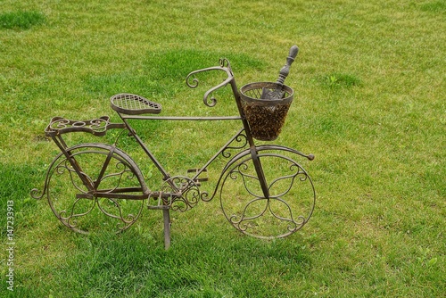 Декоративный металлический велосипед с корзинкой и совком стоящий на газоне