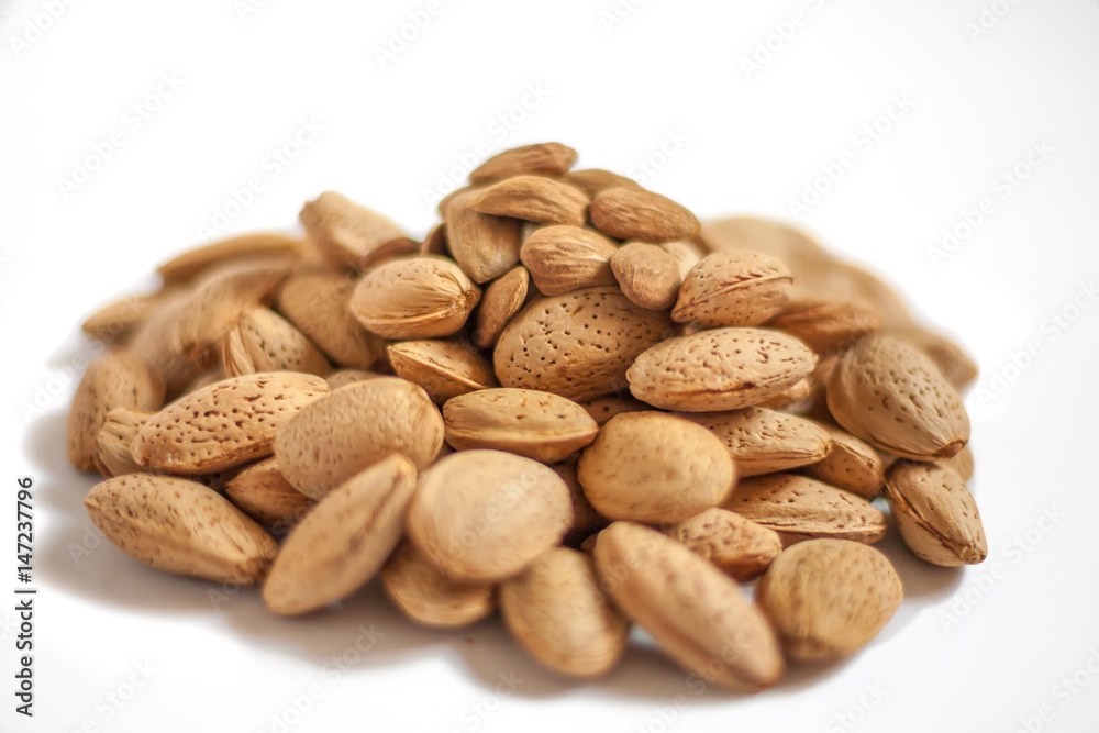 A lot of almond nuts in the shell isolated on white background, selective focus
