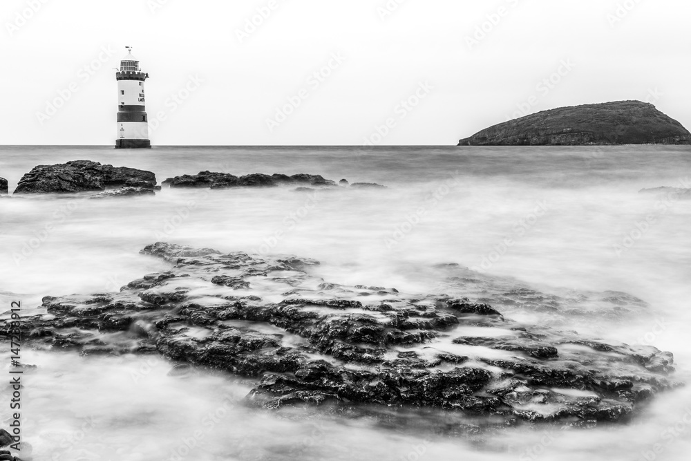 Fototapeta premium Trwyn Du or Penmon Lighthouse between Dinmor Point near Penmon and Ynys Seriol, or Puffin Island, at the eastern extremity of Anglesey North Wales. 