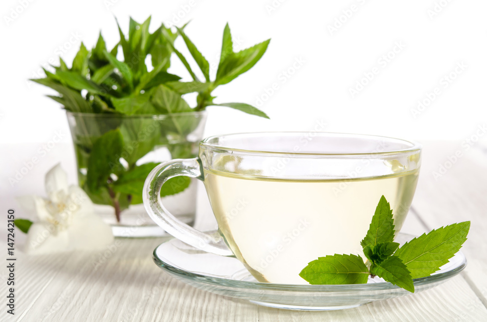Glass cup of tea with jasmine and mint on the white background Glass cup of tea with jasmine and mint on the white background