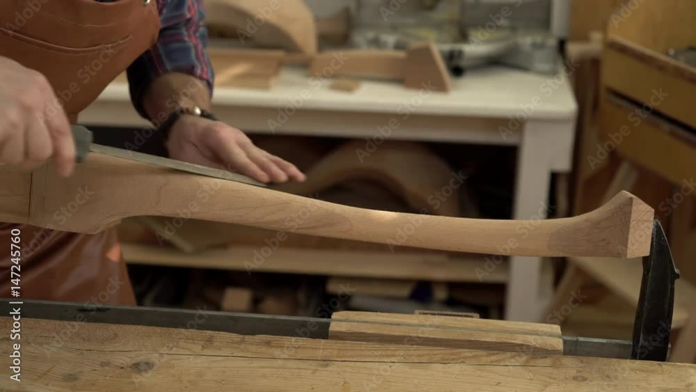 Joiner Polishes Cabrioli Leg in his Workshop/Cabinet maker polishes the cabriolet leg with a file. He works in a small family joiner’s shop. Close-up Joiner Polishes Cabrioli Leg in his Workshop/Cabinet maker polishes the cabriolet leg with a file. He works in a small family joiner’s shop. Close-up