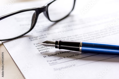 Signing the contract with pen and glasses in business work on office desk