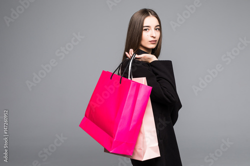 Portrait of young happy smiling woman with shopping bags on grey