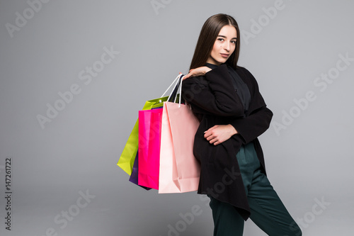 Portrait of young happy smiling woman with shopping bags, isolated over grey background