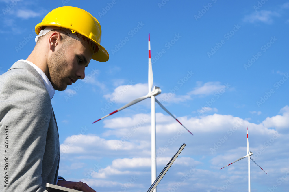 Renewable energy. Man working on his laptop in front of wind generators. Power, ecology concept. Renewable energy. Man working on his laptop in front of wind generators. Power, ecology concept.