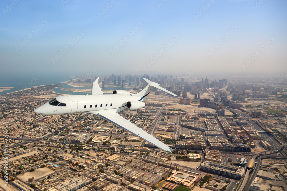 Fototapeta premium Business jet airplane flying over city.