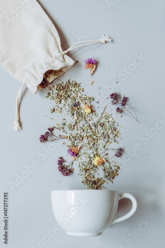 Tea time. Dry herbal tea and cup on the gray background, top view