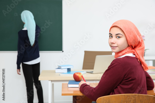 Cute girl sitting at desk i...