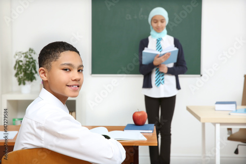 Cute boy sitting at desk in...