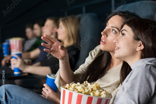 Two female friends watching a movie at the cinema together
