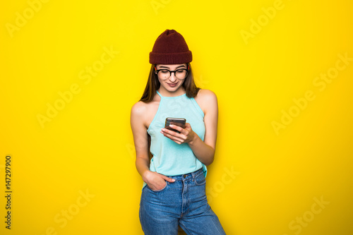 Portrait of confused woman with mobile phone on the yellow background
