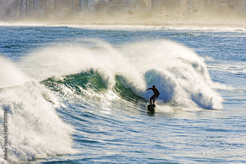 Fototapeta Naklejka Na Ścianę i Meble -  Surfer and wave with water spray at Ipanema beach in Rio de Janeiro