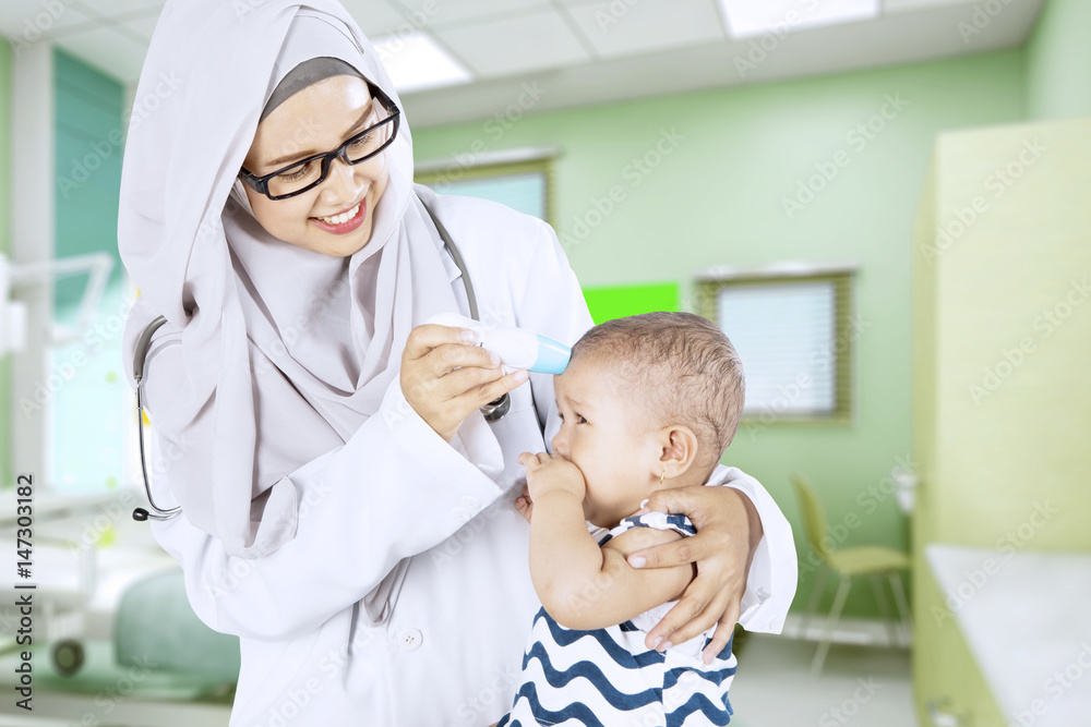 Pediatrician uses thermometer to check baby Pediatrician uses thermometer to check baby