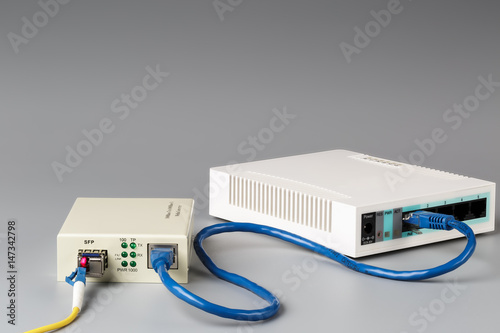 Media converter with optical patchcord and router connected via copper cable photo