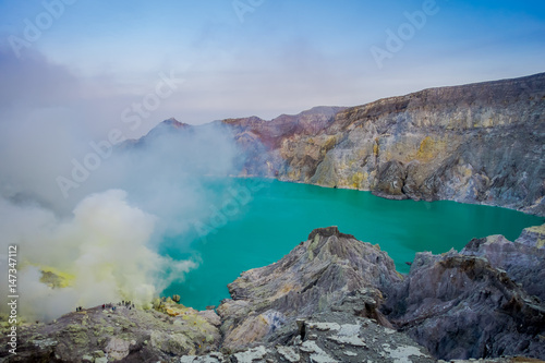 KAWEH IJEN, INDONESIA: Tourist hikers with backpacks and facial masks seen overlooking sulfur mine and volcanic crater