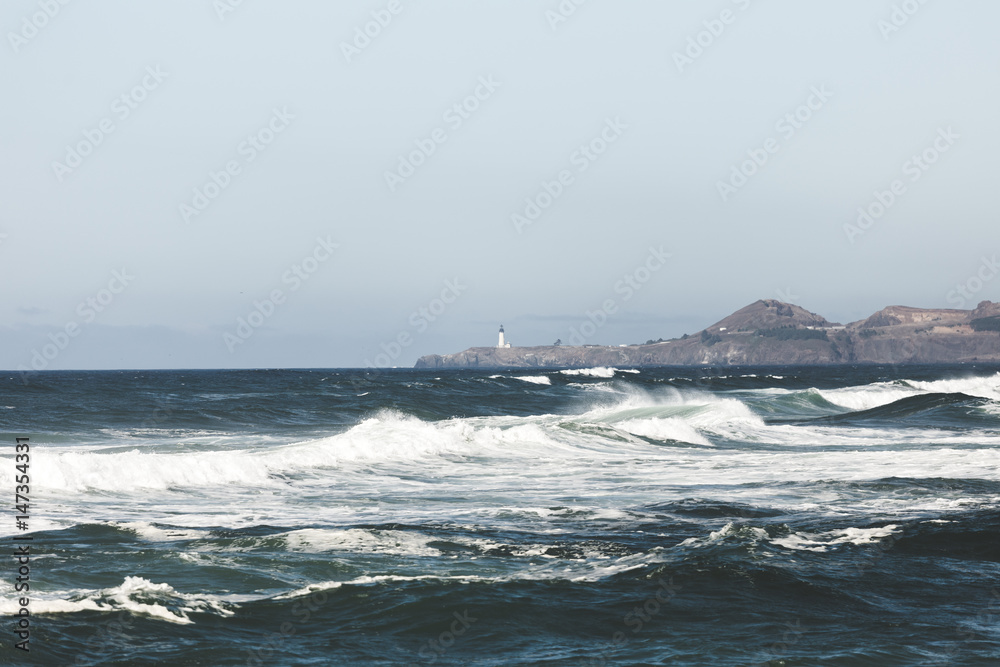 Waves Breaking Near Shore and Distant Lighthouse