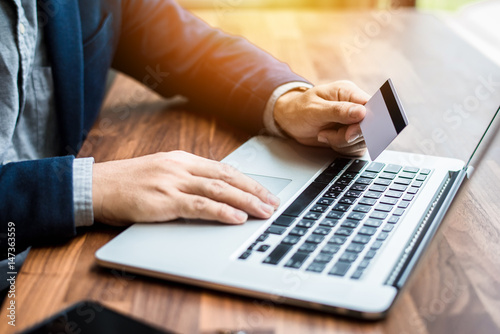 Handsome businessman in suit and eyeglasses Hands holding credit card and using laptop. Online shopping,Side view Hands holding credit card and using laptop. Online shopping