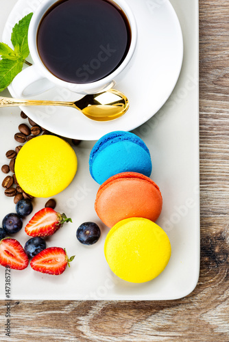 Photo of macaroons and berries on wooden background