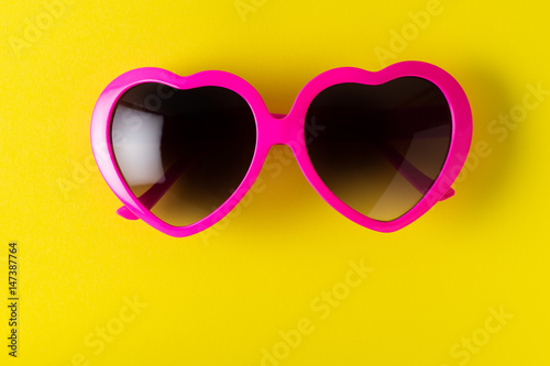 pink heart-shaped sunglasses isolated on yellow background