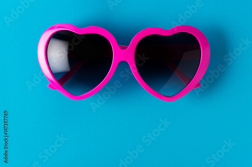 pink heart-shaped sunglasses isolated on blue background