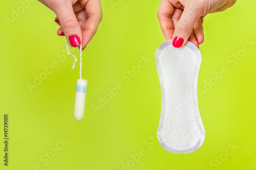 Woman holding tampon and sanitary napkin in hands